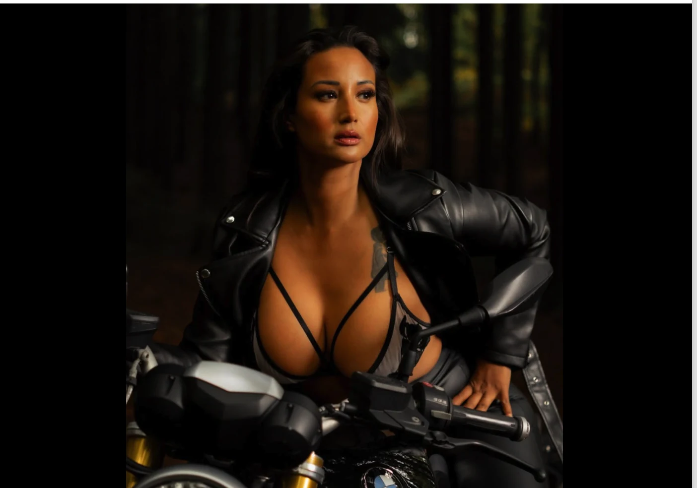 Nadia in black leather on a BMW motorcycle in a dark forest